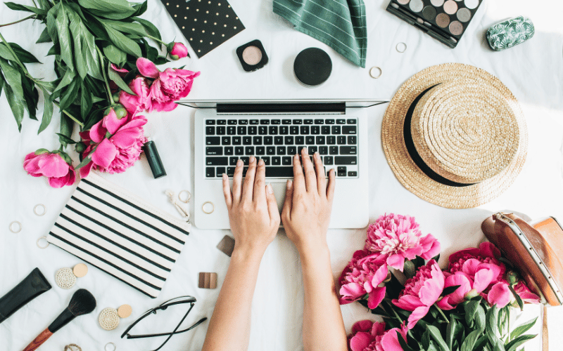 Spring Marketing - hand typing on a laptop surrounded with flowers