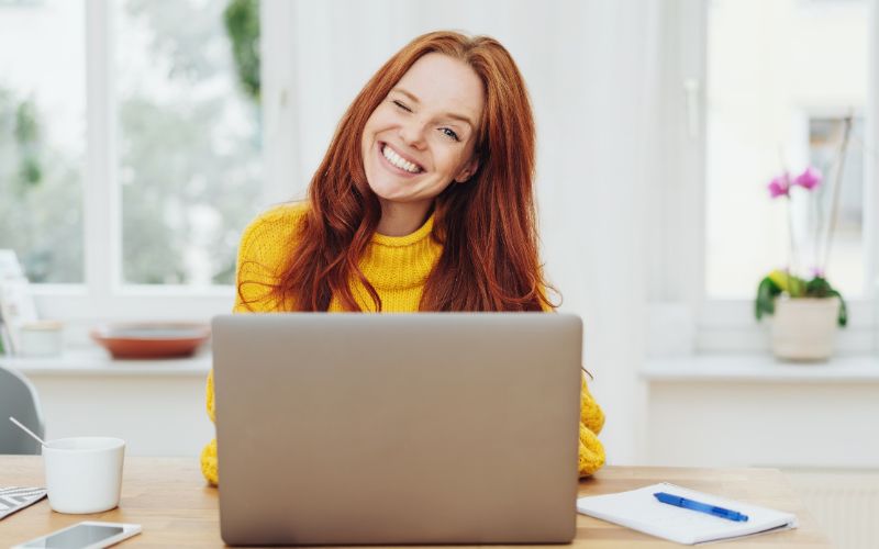 2024 marketing - woman in front of a laptop happily looking at the camera with a wink